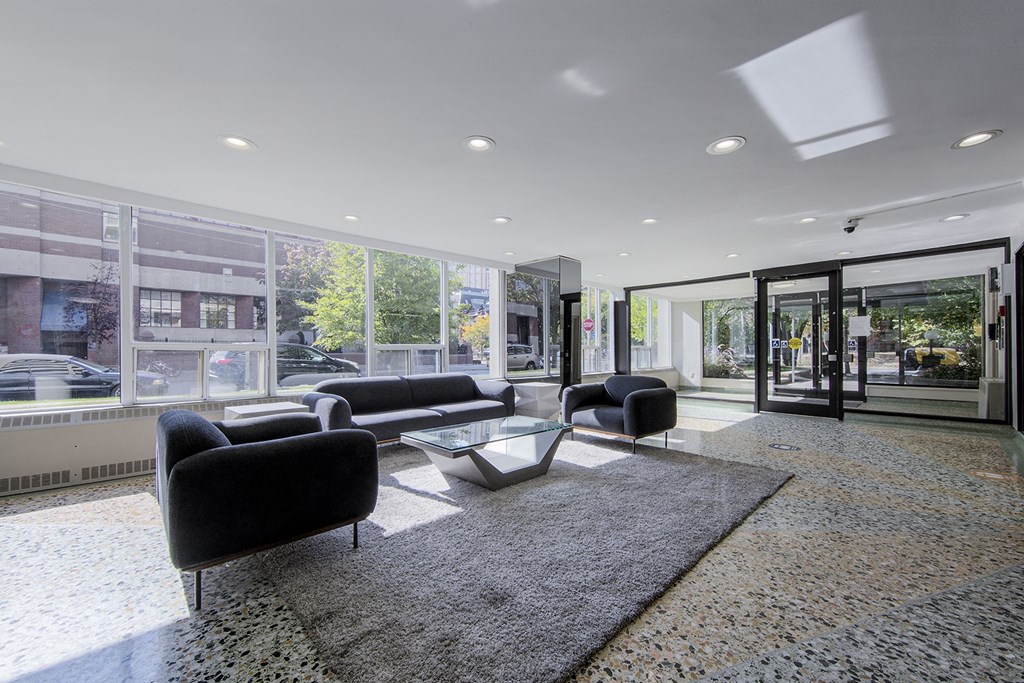 A black sofa and chair are in a room with a glass wall.