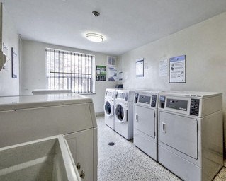 A laundry room with a washer and dryer on the wall and a sink in the foreground.