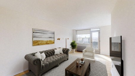 A living room with a grey couch and a painting on the wall.