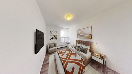 A bedroom with a bed, a chair, and a television.