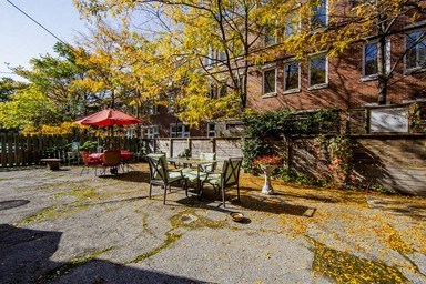 A patio with a table and chairs surrounded by trees with yellow leaves.