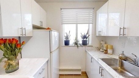 A kitchen with white cabinets and a white fridge.