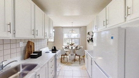 A kitchen with white cabinets and a white fridge.