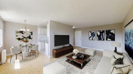 A living room with a white couch, a coffee table, and a television.