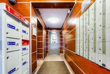 A hallway with a series of lockers on the right and a door at the end.