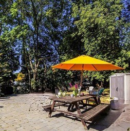 A yellow umbrella is on a wooden table outside.