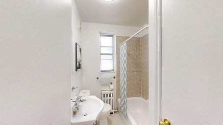 A white bathroom with a tub, sink, and window.