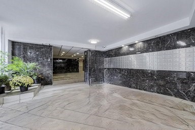 A hallway with marble floors and walls, and a potted plant on the left.