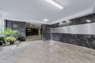A hallway with marble floors and walls, and a potted plant on the left.