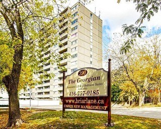 A sign for The Georgian apartment building stands in front of a tall building.
