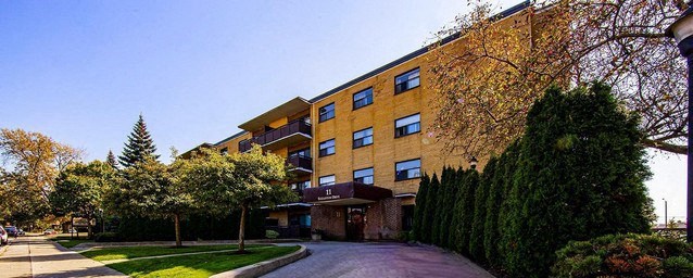 A large building with a yellow facade is surrounded by greenery.