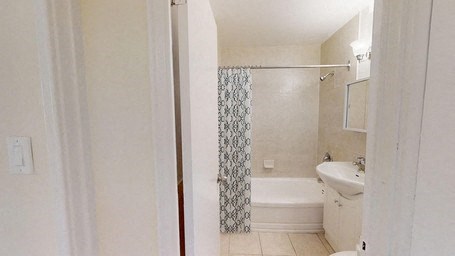 A white bathroom with a shower curtain and a white sink.