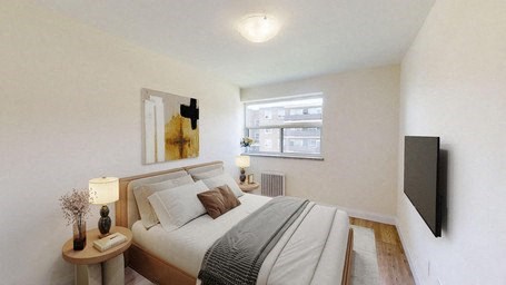 A bedroom with a bed, nightstand, and a window.