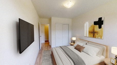 A bedroom with a bed, a television, and a painting on the wall.