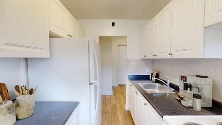A kitchen with white cabinets and a white refrigerator.