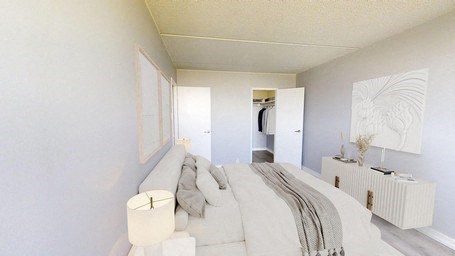 A white bedroom with a bed and a lamp.