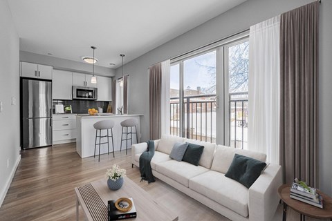 A modern living room with a white sofa and a kitchen area in the background.