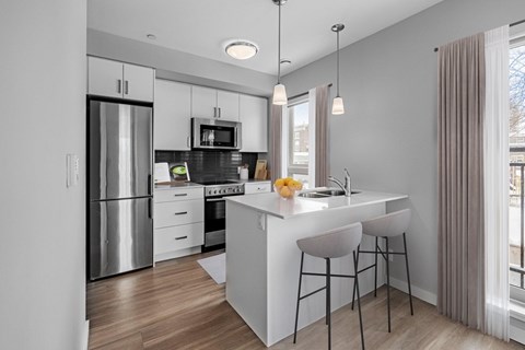 A modern kitchen with a white island and bar stools.