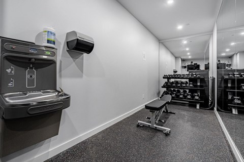 A black and white photo of a gym with a row of dumbbells.
