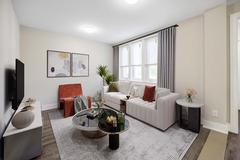 A living room with a grey sofa, a red chair, a coffee table, and a flat screen TV.