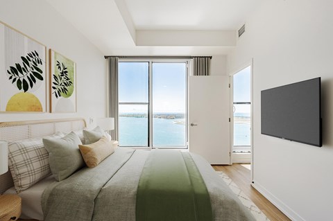 A bedroom with a large bed and a flat screen TV mounted on the wall.