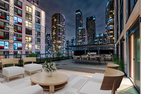 A patio with a table and chairs overlooks a city skyline at night.