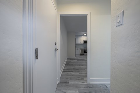 A hallway with a white door and a white wall.