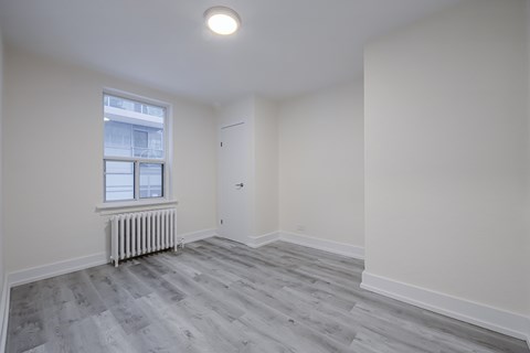 A room with a grey floor and a window with white blinds.