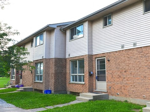 A two-story brick house with a grey roof and white siding.