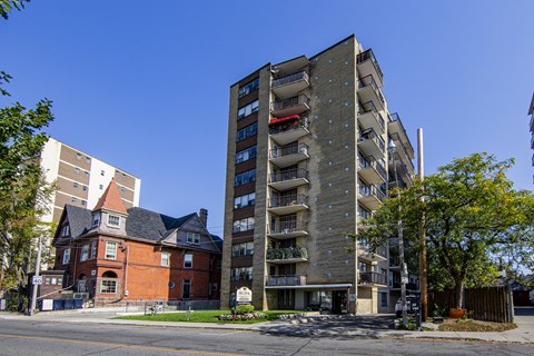 A tall apartment building with balconies is in the foreground of a street scene.