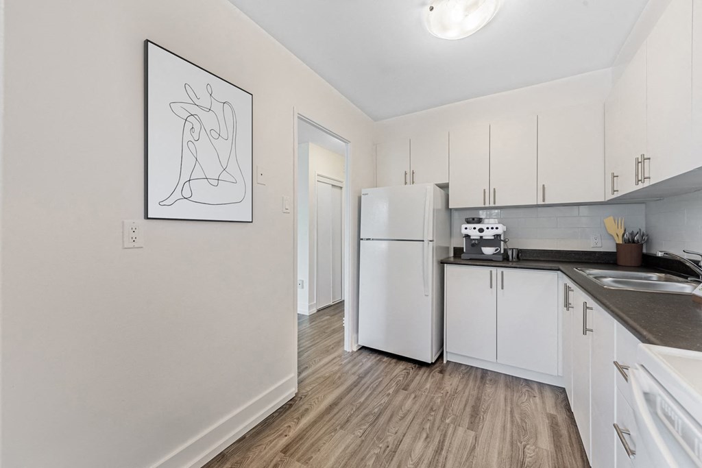 A kitchen with white cabinets and a fridge.