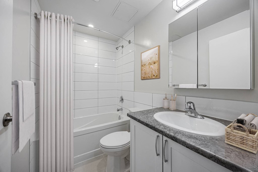 A bathroom with a white toilet, a sink, and a shower.