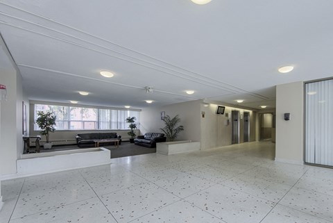 A spacious room with white tiled flooring and a large window.