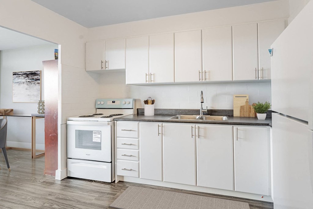 A kitchen with white cabinets and a black countertop.