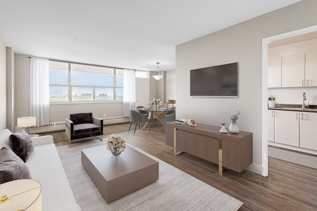 A modern living room with a grey sofa, a coffee table, and a flat-screen TV mounted on the wall.