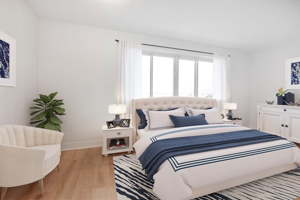A bedroom with a large bed and a white chair.
