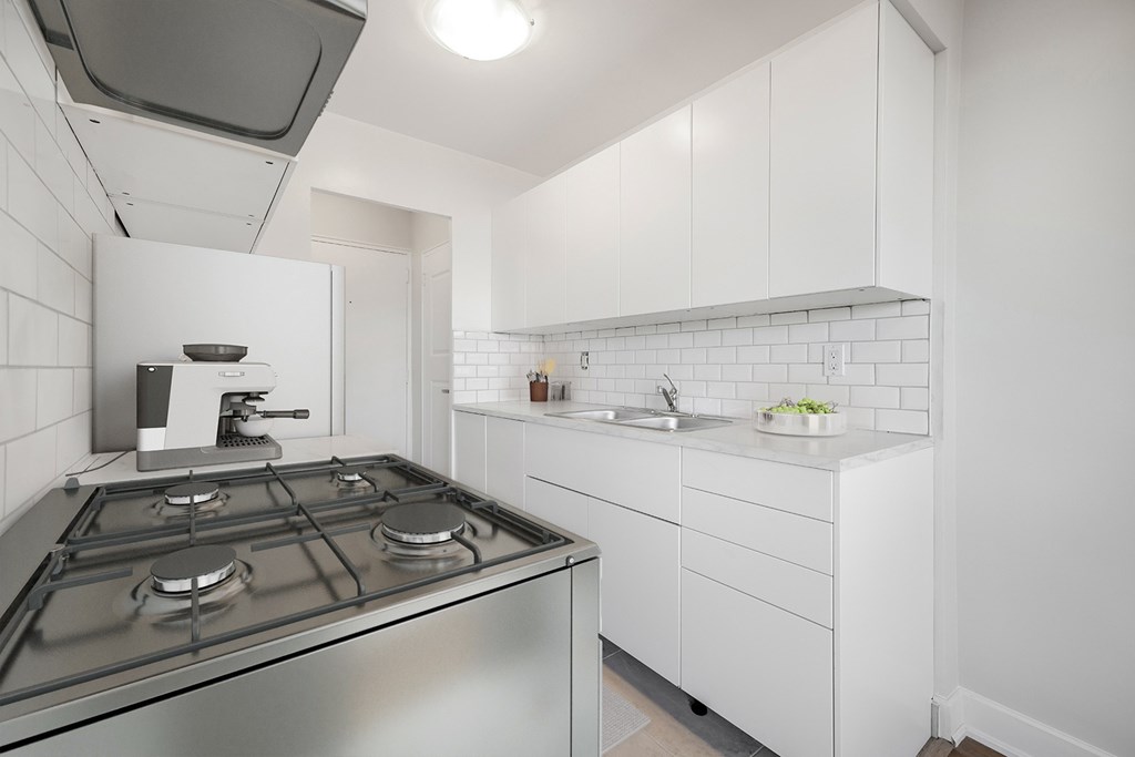A modern kitchen with a stainless steel stove and white cabinets.