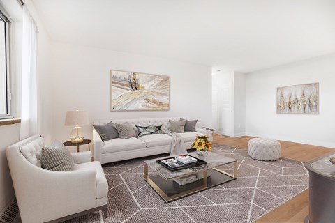 A living room with a white couch, a coffee table, and two chairs.