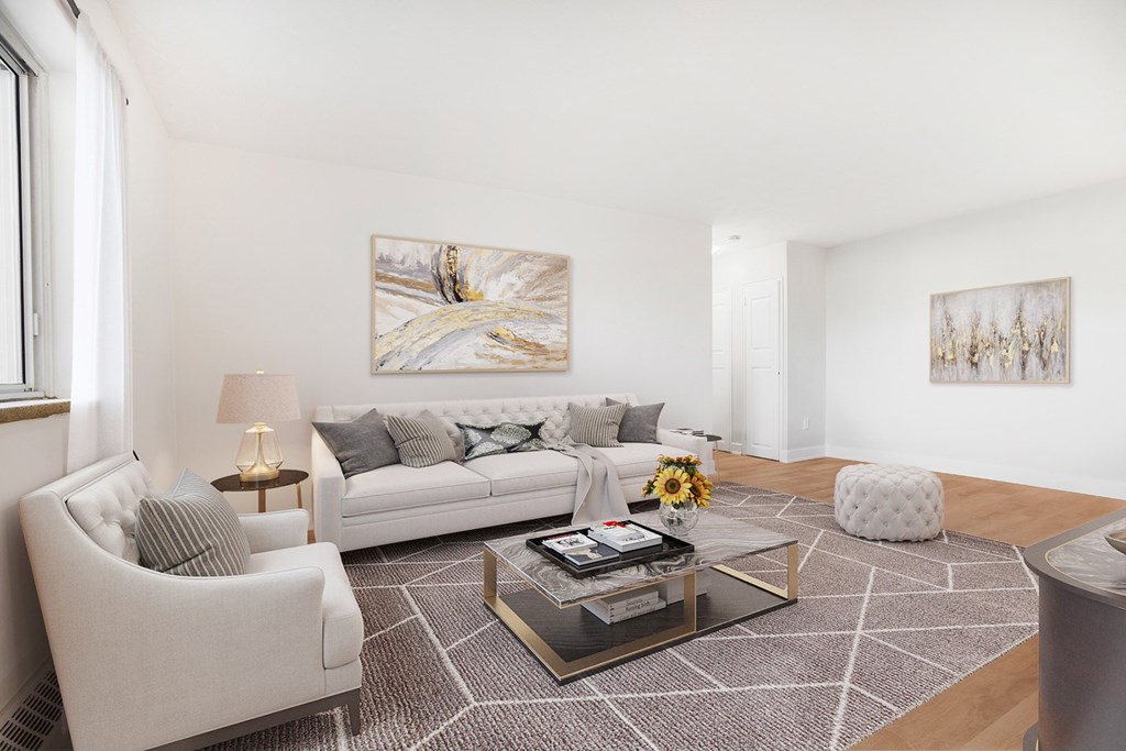 A living room with a white couch, a coffee table, and two chairs.