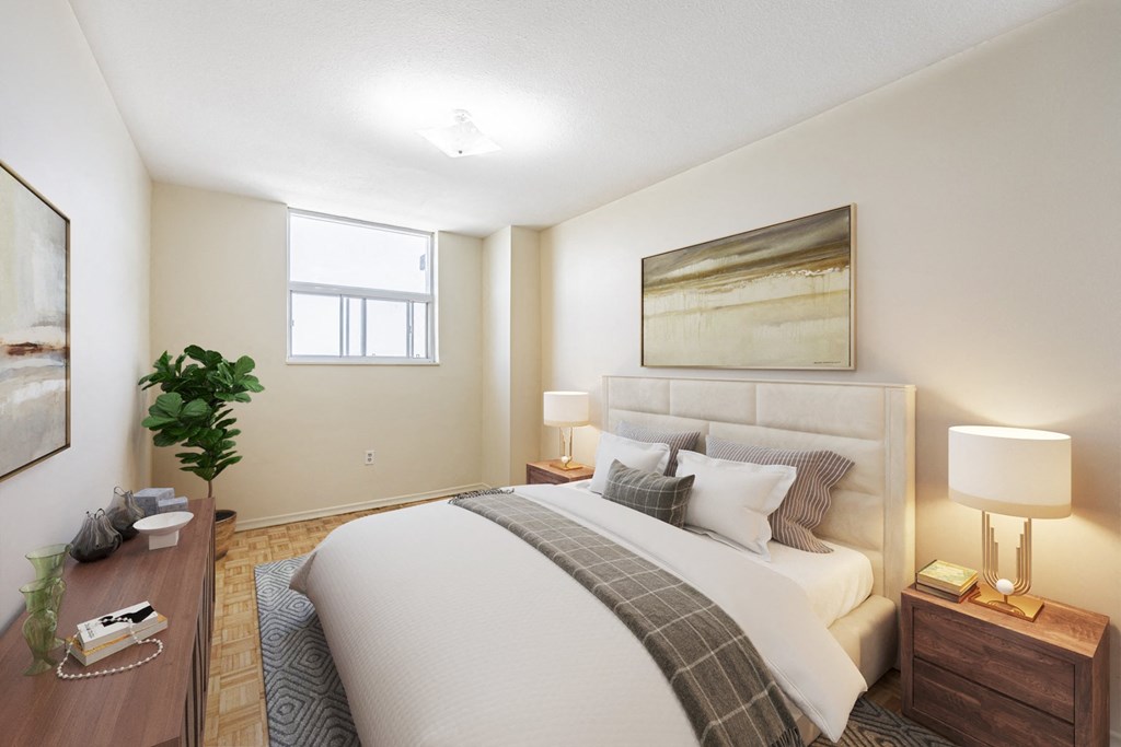 A well-lit bedroom with a large bed, a nightstand with a lamp, and a potted plant.