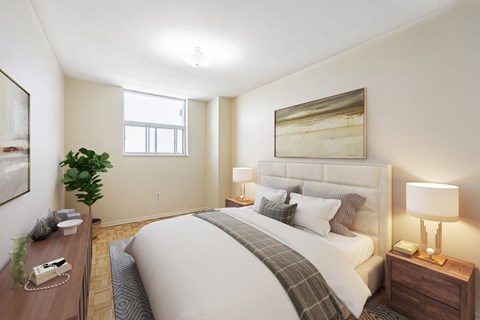A well-lit bedroom with a large bed, a nightstand with a lamp, and a potted plant.