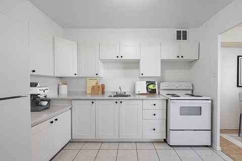 A white kitchen with a stove, oven, and cabinets.