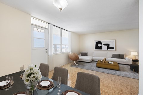 A dining room with a table set for two and a couch in the background.