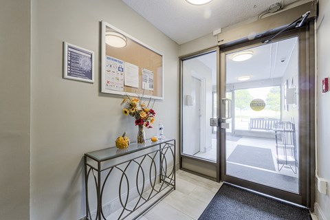 A hallway with a glass console table and a mirror above it.