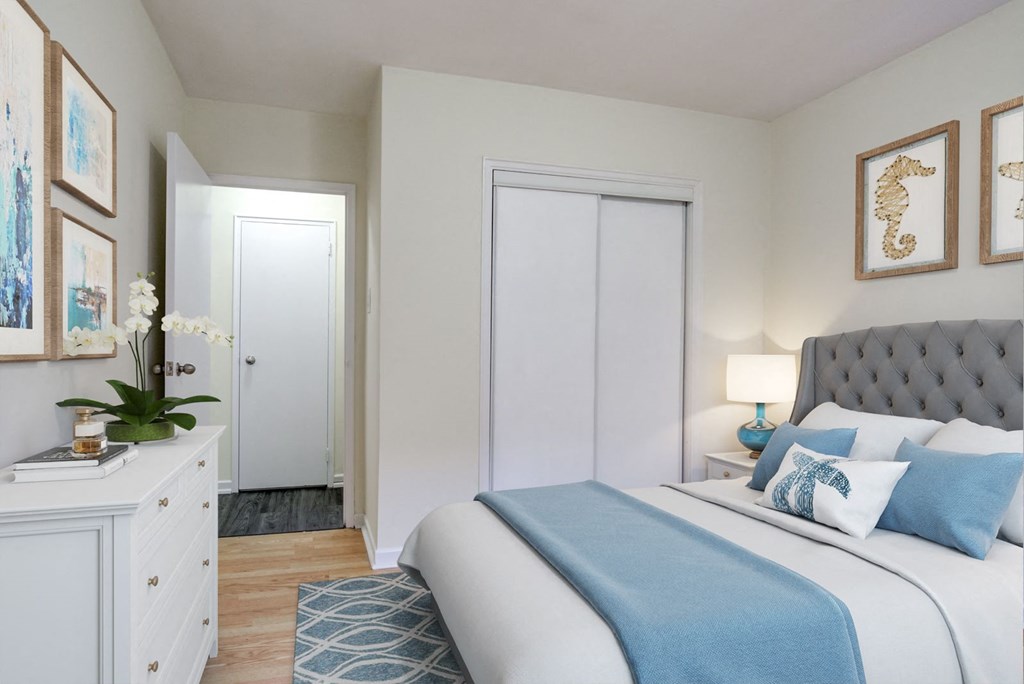 A bedroom with a bed, nightstand, and a dresser with a plant on top.