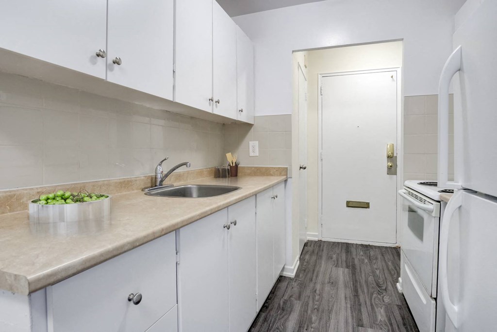 A kitchen with white cabinets and a wooden floor.