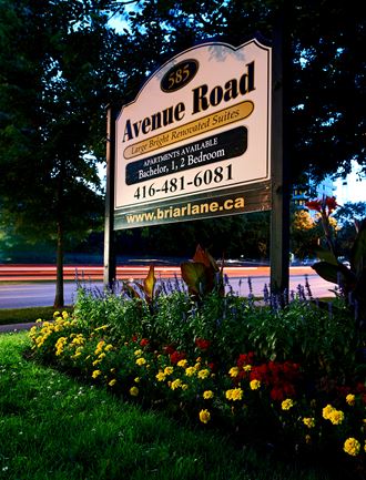 a sign for avenue road in front of a flower garden