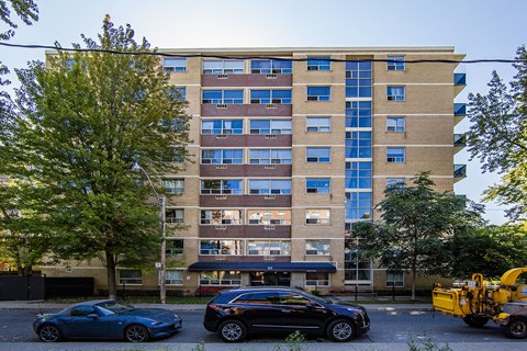A large building with a lot of windows and cars parked in front.