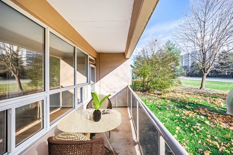 A balcony with a table and chairs overlooking a garden.