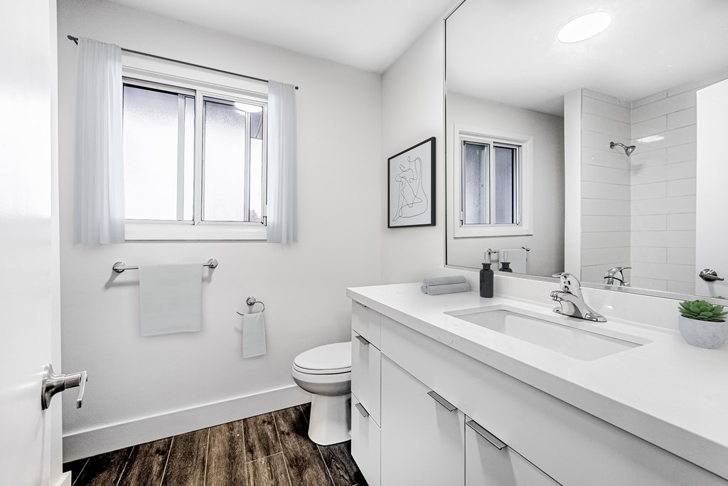 A white bathroom with a toilet, sink, and mirror.